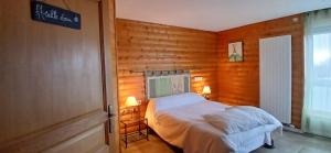 a bedroom with a bed in a room with wooden walls at Appartement les Coquelicots Super Besse in Besse-et-Saint-Anastaise