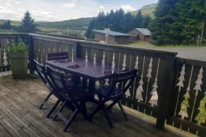 a wooden deck with a table and chairs on it at Appartement les Coquelicots Super Besse in Besse-et-Saint-Anastaise