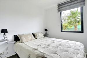 a white bedroom with a large bed with a window at FAA'mily Home, 3 bedrooms, meublé de tourisme 4 étoiles in Offemont