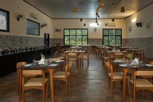 a restaurant with tables and chairs in a room at Sonemale Resort Chikmagalur in Mudigere