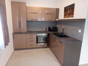 a kitchen with brown cabinets and a sink and a stove at President Apartmanház - Nincs szomszéd - Egy időben,egy társaság - in Békéscsaba