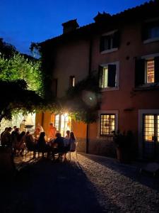 een groep mensen die aan een tafel voor een gebouw zitten bij Villa Avesa in Verona