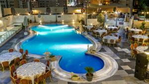 a large swimming pool with tables and chairs at Days Inn Hotel & Suites Amman in Amman