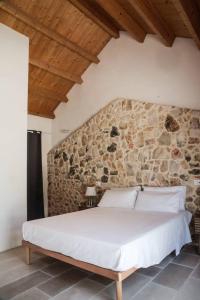 un letto in una stanza con un muro di pietra di Masseria Voluzzi a Copertino Altre 54 foto