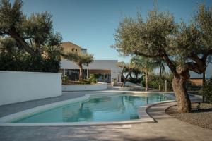 einem Pool mit Bäumen vor einem Gebäude in der Unterkunft Villa Teresa in Cefalú