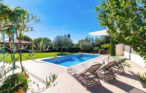 a swimming pool with two chairs and an umbrella at House Moreda by Istrialux in Vodnjan