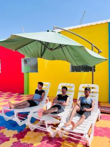 drie mannen zitten in tuinstoelen onder een parasol bij Mahi Baagh Resort in Pāli