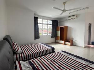 een slaapkamer met twee bedden en een raam bij Homestay 76 in Mersing