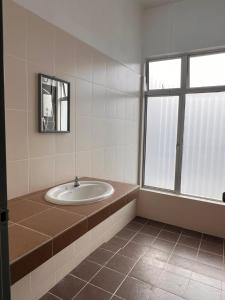 een badkamer met een wastafel en een raam bij Homestay 76 in Mersing