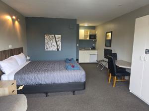 ein Schlafzimmer mit Bett und Schreibtisch und eine Küche in der Unterkunft Palmcourt Motel in Westport