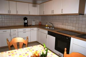 a kitchen with white cabinets and a sink and a table at Ferienwohnung Schuhmacher in Donaueschingen
