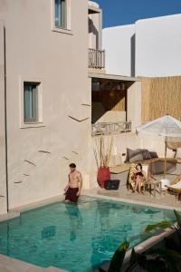 a man standing in the water in a swimming pool at Salt Suites Paros in Naousa