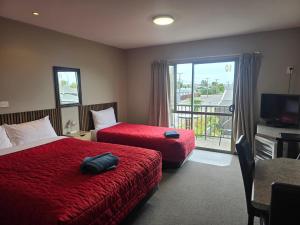 ein Hotelzimmer mit zwei Betten und Balkon in der Unterkunft Palmcourt Motel in Westport
