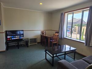 ein Wohnzimmer mit einer Couch, einem Tisch und einem Fernseher in der Unterkunft Palmcourt Motel in Westport