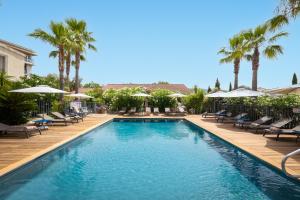 a swimming pool with chairs and umbrellas and palm trees at Golfe Hôtel & Spa Porto-Vecchio in Porto-Vecchio