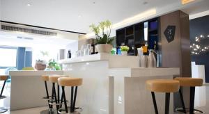 a kitchen with a white counter with stools at Echarm Hotel Guiyang International Convention & Exhibition Center in Guiyang