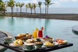 ein Tisch mit Tellern voller Essen neben einem Pool in der Unterkunft Quenzo Beach Resort in Padangbai