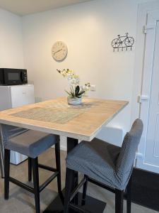een eettafel met 2 stoelen en een klok aan de muur bij Appartement La Gare-rdc in Saint-Gaudens