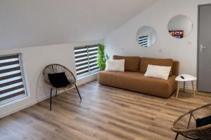 a living room with a couch and two windows at Appart Hotel 23 - Le Cocon Creusois 2 in Guéret
