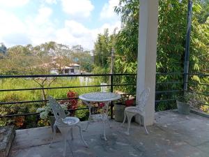 einen Tisch und Stühle auf einem Balkon mit Flussblick in der Unterkunft Barefoot Inn Kandy in Kandy