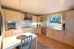 una cucina con mobili bianchi, tavolo e sedie di Ferienwohnung Captains Lodge Steinbergkirche a Steinbergkirche