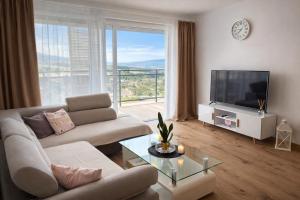 a living room with a couch and a large window at Modern Smart Apartment, Garage & City View in Lipany