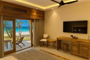 een woonkamer met een televisie en een bureau met stoelen bij JAZ Adonia in Uroa