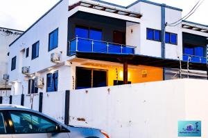 una casa bianca con un'auto parcheggiata davanti di Ernest homes a Kwabenyan
