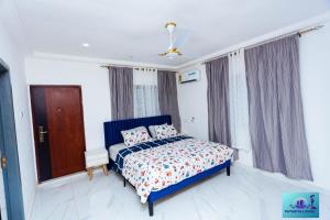 una camera da letto con un letto blu e cuscini sopra di Ernest homes a Kwabenyan