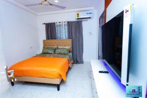 una camera da letto con un letto e una TV a schermo piatto di Ernest homes a Kwabenyan