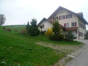 a house with animals in a field next to a house at Ferienwohnung Bio-Bauernhof Schuwerk in Isny im Allgäu