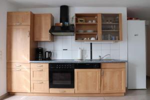 a kitchen with wooden cabinets and a white refrigerator at Ferienwohnung Bio-Bauernhof Schuwerk in Isny im Allgäu