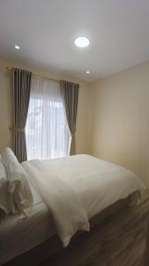 ein Schlafzimmer mit einem weißen Bett mit einem Fenster in der Unterkunft Villa Dalia Puncak H11-11 in Cikundul