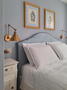 ein Schlafzimmer mit einem weißen Bett mit zwei Bildern an der Wand in der Unterkunft al piccolo giardino in Vittorio Veneto