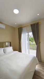ein Schlafzimmer mit einem großen weißen Bett und einem Fenster in der Unterkunft Villa Dalia Puncak H11-11 in Cikundul