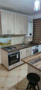 una cucina con piano cottura e bancone con sgabello di E&A apartments a Târgu-Mureş