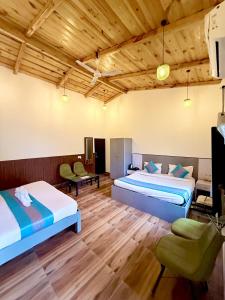 a hotel room with two beds and a tv at Shelton Blu Resort By Mango People in Rāmnagar