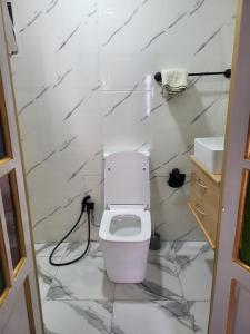 a white bathroom with a toilet and a sink at Akwaba lodge in Salé