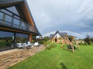 ein Haus mit einem Spielplatz und einem Regenbogen im Hintergrund in der Unterkunft Białczańskie Bacówki 2, 4sypialnie in Białka Tatrzańska