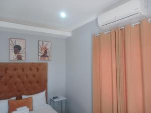 a bedroom with a bed with an orange curtain at Red Hills Guesthouse in Tsumeb