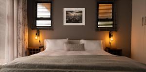 a bedroom with a large bed with two windows at Essea House in Wilderness