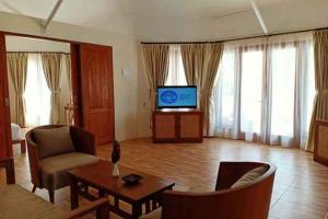 DehegilaMarahai Villa Morotai的带电视、沙发和桌子的客厅