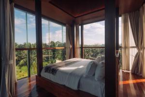 a bedroom with a bed and a large window at Soulshine Resort Ubud, Bali in Ubud
