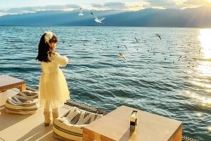 a young girl standing on a boat looking at birds at LIUBAI HANDANYI Seaview Resort Hotel in Dali Shuanglang