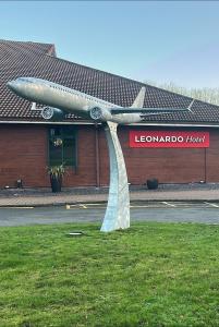 Una estatua de un avión en el césped frente a un edificio. en Leonardo Hotel East Midlands Airport, en Castle Donington
