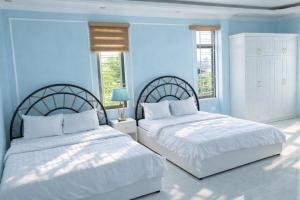 two beds in a bedroom with blue walls and windows at King Hotel Hải Phòng in Hai Phong