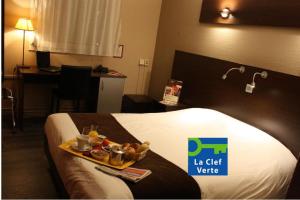 a hotel room with a tray of food on a bed at The Originals City, Hôtel Ascotel, Lille Est Grand Stade in Villeneuve d'Ascq