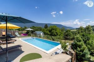 einen Pool mit Sonnenschirm und einigen Stühlen in der Unterkunft La grange du paris in Saint-Pierre-dʼAlvey