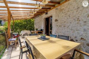 eine Terrasse mit einem Tisch, Stühlen und einer Steinmauer in der Unterkunft La grange du paris in Saint-Pierre-dʼAlvey
