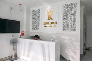 a man sitting at a reception desk in a white room at King Hotel Hải Phòng in Hai Phong
